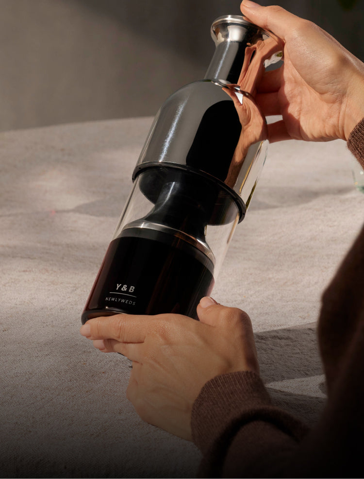 Two hands holding and admiring an engraved eto wine decanter and preserver