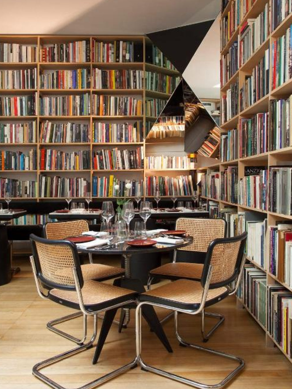 Dining table with chairs in a room filled with bookshelves.