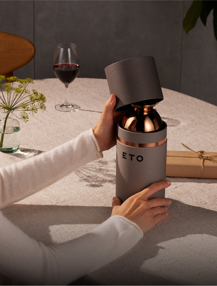 A woman opens the grey kraft paper packaging of the ETO on a linen tablecloth