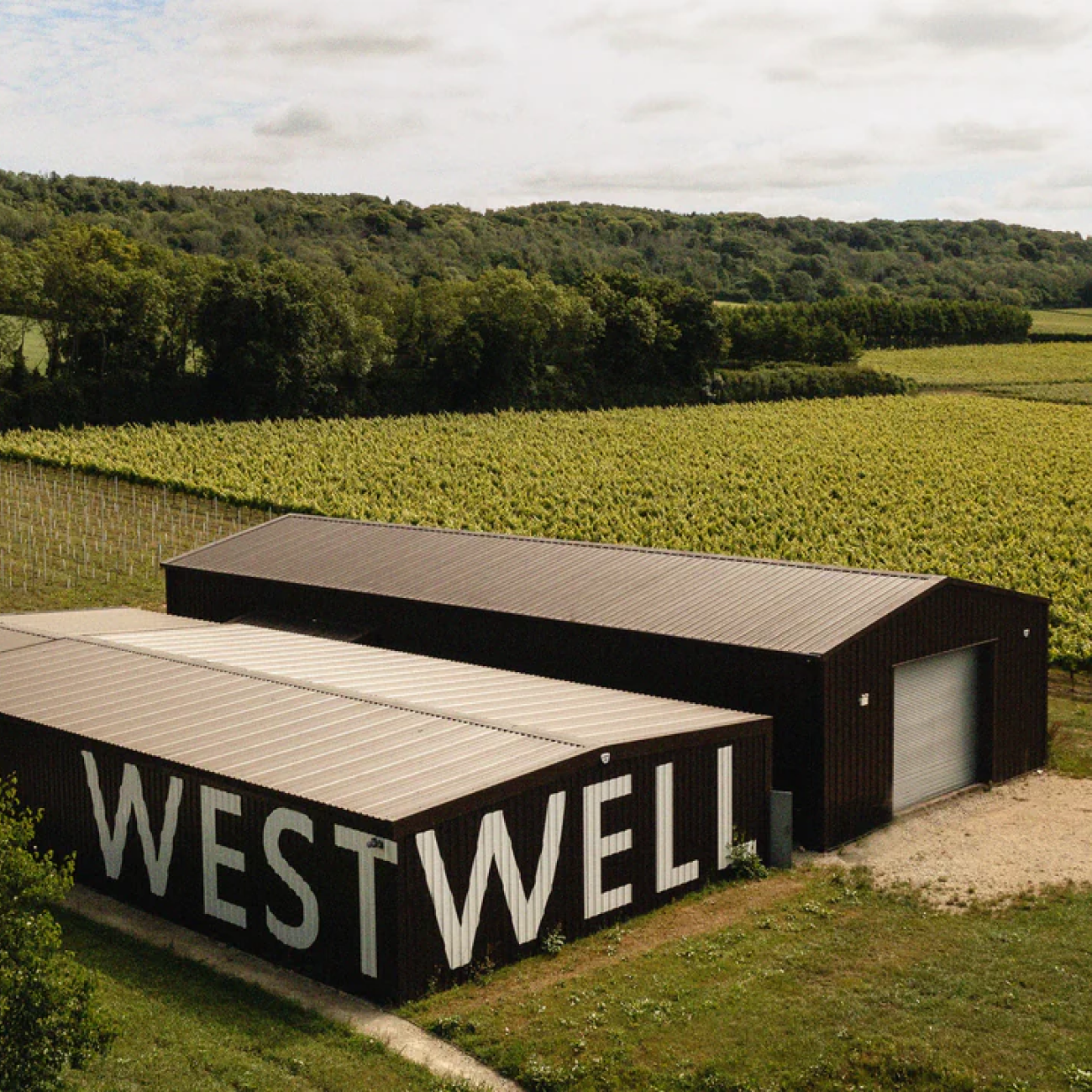 Modern building with 'WESTWELL' branding in a rural setting with fields and trees.