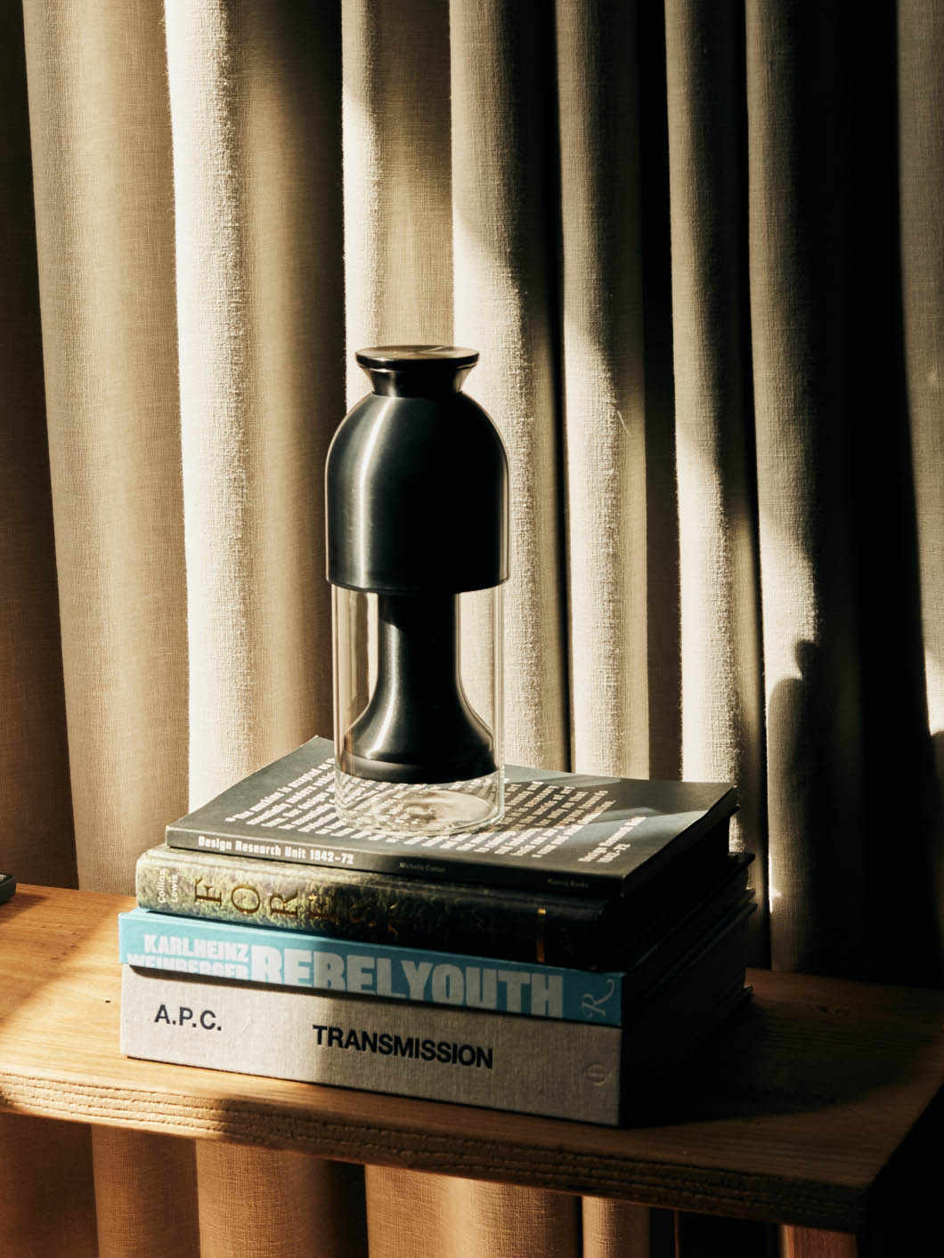 an eto wine decanter in a graphite satin finish sitting on a stack of coffee table books in sunlight