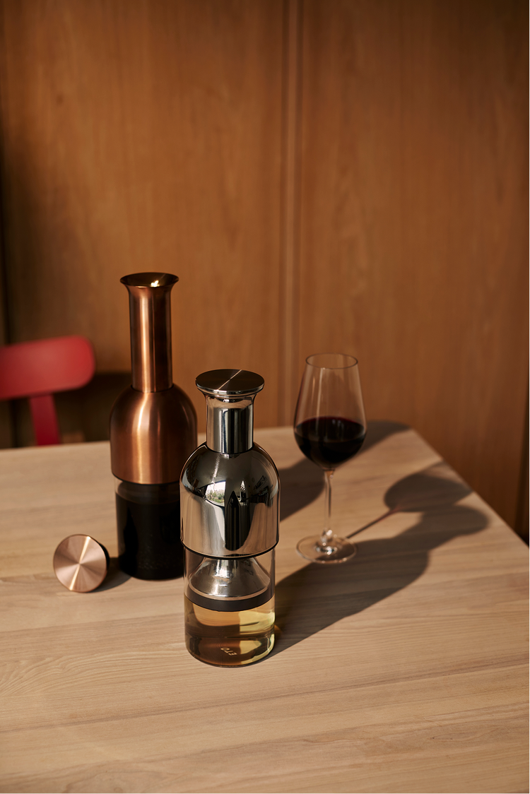 Two ETO wine decanter's on a wooden table with a wooden wall in the background