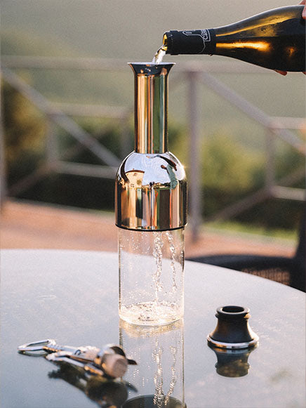 a bottle of white wine being poured into an eto wine decanter in stainless steel